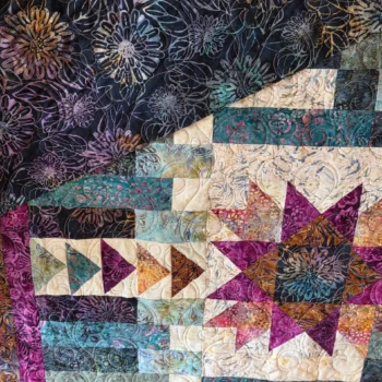 Colorful quilt with geometric and floral patterns.