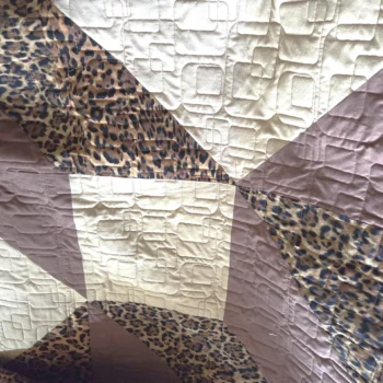 Patchwork quilt with leopard and geometric patterns.