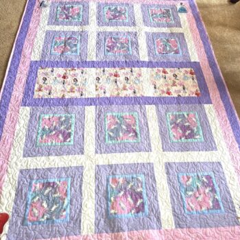 Quilt with purple and pink square patterns.