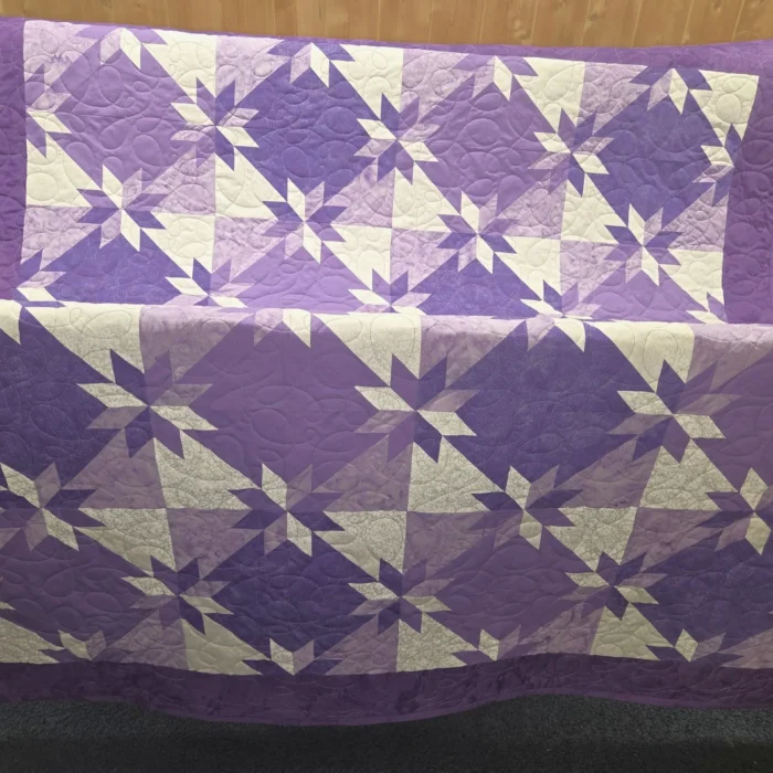 Purple and white star-patterned quilt displayed.
