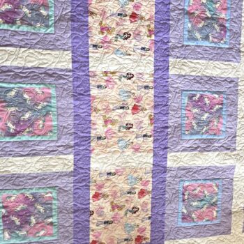 Patchwork quilt with purple and pink squares.