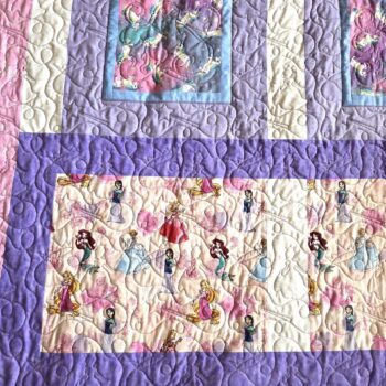 Colorful quilt with princess-themed fabric squares.